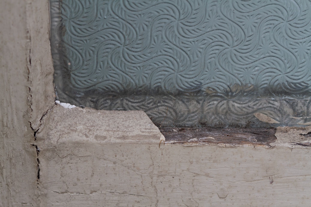 Close-up photo of an decorative window with cracked wood molding
