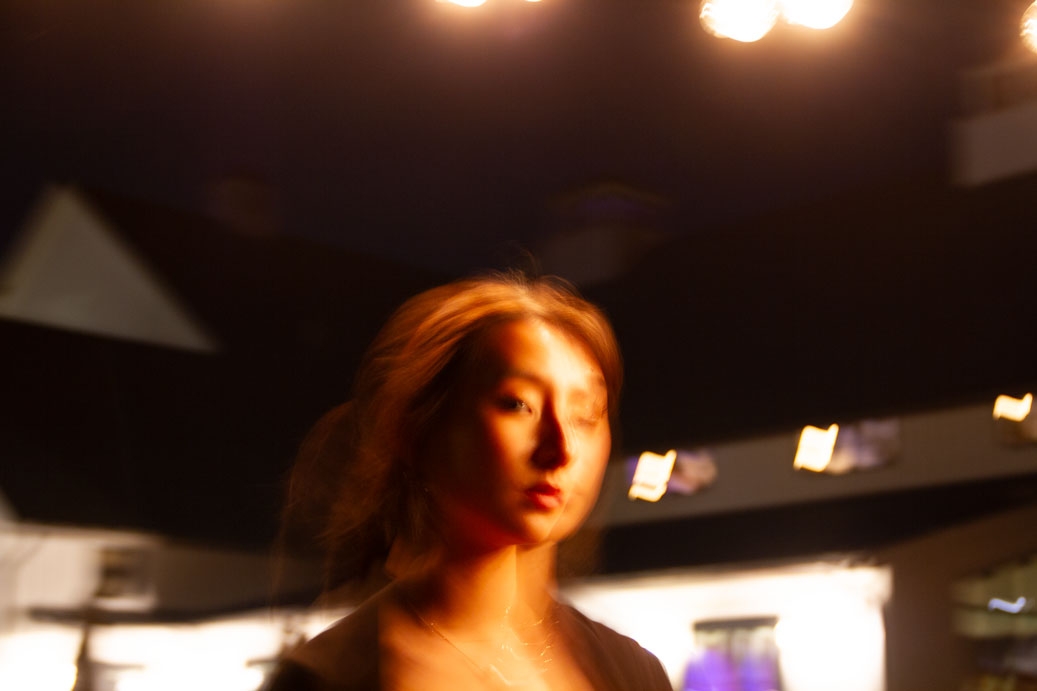 Blurry picture of a girl at night lit by string lights