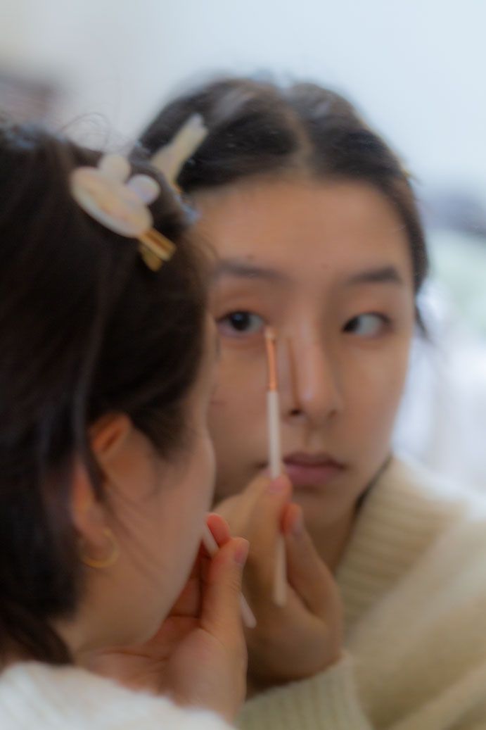 Girl applying makeup reflected in a mirror