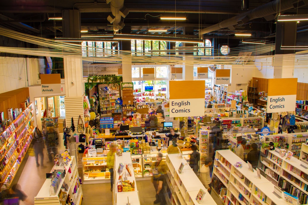 Interior photo of Portland's Kinokuniya Japanese bookstore, with blurred/transparent figures